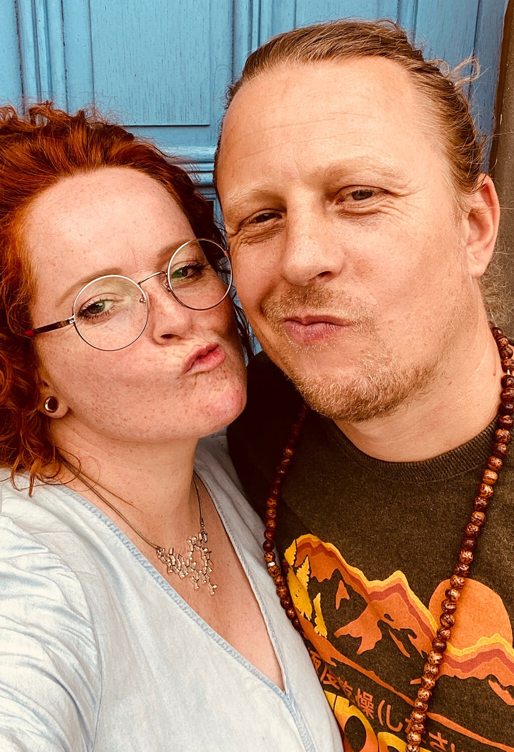 ginny-warner-doula-bij-rouw-en-sterven-liefde-thijs Ginny Warner en haar partner Thijs geven luchtkusjes voor een blauwe houten deur in België